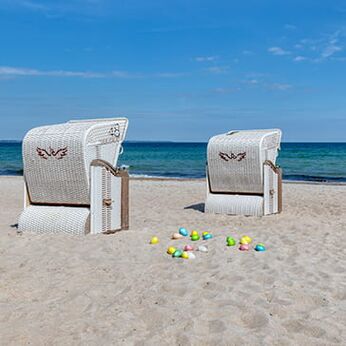 Strandkörbe am Sandstrand mit bunten Ostereiern vor der Ostsee