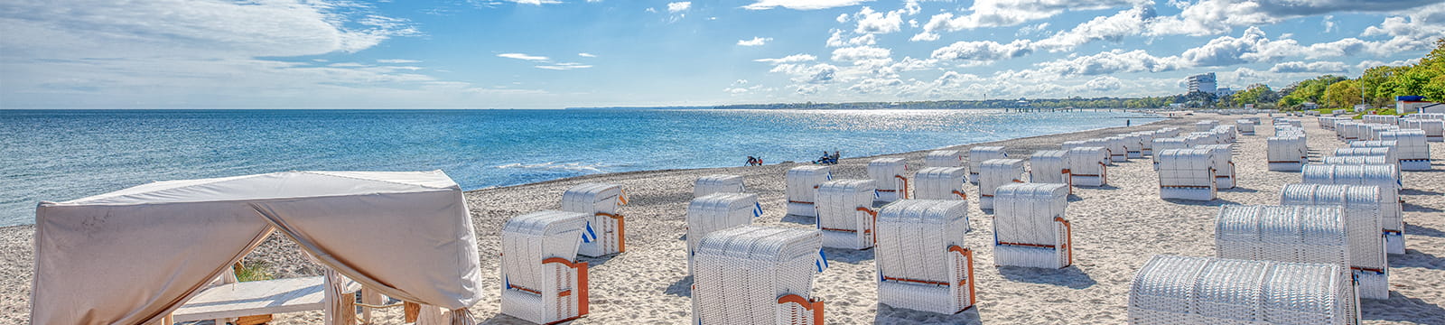 Strandkörbe am Strand von Timmendorfer Strand mit Meerblick und blauem Himmel.
